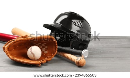 Baseball glove, bats, ball and batting helmet on grey wooden table against white background