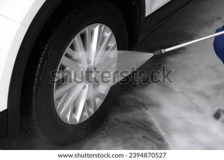 Washing auto with high pressure water jet at outdoor car wash, closeup Royalty-Free Stock Photo #2394870527
