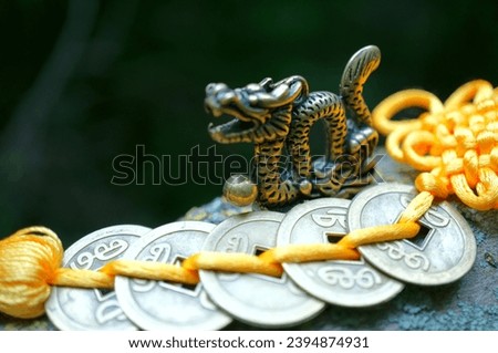 A metal dragon figurine and Chinese coins. Amulets and talismans. Royalty-Free Stock Photo #2394874931