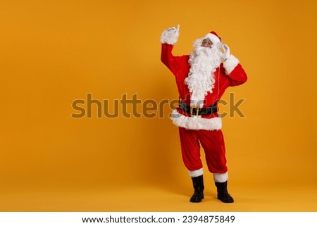 Merry Christmas. Santa Claus in headphones listening to music on orange background, space for text