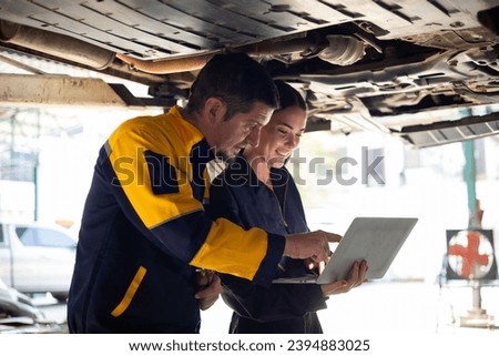 apprentice. Caucasian Female trainee Mechanics Working Underneath Car with male Instructor at Car maintenance and auto service garage. Car maintenance and auto service garage concept.  Royalty-Free Stock Photo #2394883025