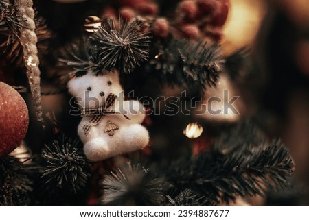White soft toy polar bear figurine hanging on a Christmas tree branches