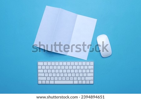 Blank white paper with wireless keyboard and mouse on blue background