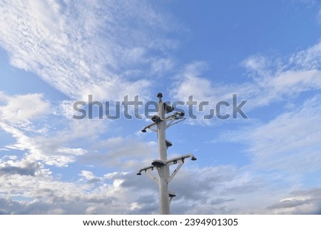 The masthead on a ship, commonly known as the mast, is a vertical structure rising above the deck, With the sky and clouds background.