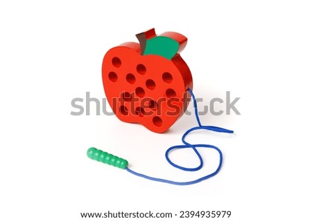 Children's wooden toy in the shape of a red apple with a worm on a rope isolated on white background.