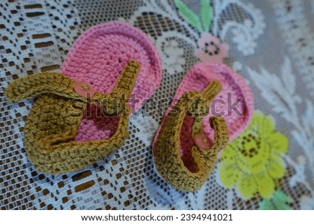 These pink knitted baby flip-flops featuring charming brown straps, artfully displayed on a white tablecloth. Ideal for baby fashion concepts