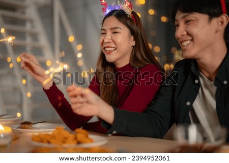 men and women holding sparkler fireworks in a party with Christmas tree. young couple Asian people enjoy celebrating Christmas and New Year. happy and celebrate with food wine and friendship for love,