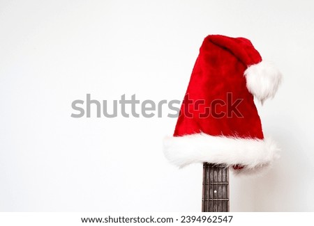 Red Christmas hat on guitar with white background, Merry Christmas song