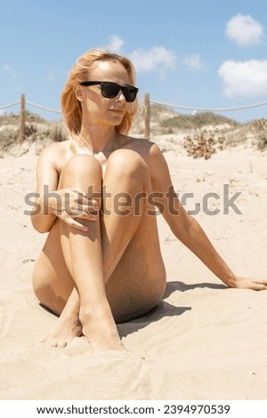 sporty girl sitting on the beach wearing sunglasses, there is a place for the inscription Summer 