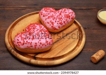 pink donuts in the shape of a heart on a wooden board close up