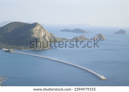 Picture of a mountain view in the middle of the sea and a white walkway