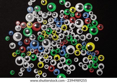 Various sizes and color of funny kids art googly eyes on black background
