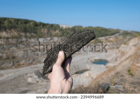 A scenic landscape showing a mining site with a prominent graphite deposit, heavy mineral production equipment, and natural rock formations in the surrounding area. Royalty-Free Stock Photo #2394996689