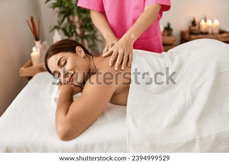 Young beautiful hispanic woman lying on table having back massage at beauty salon