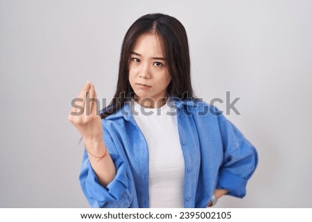 Young chinese woman standing over white background doing italian gesture with hand and fingers confident expression 