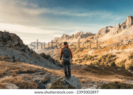 Male hiker hiking with enjoying the French Alps scenic and massif Des Cerces on autumn wilderness in Claree Valley at Hautes Alpes, France Royalty-Free Stock Photo #2395002897