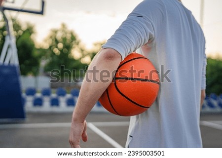 midsection of One unknown teenager caucasian male caucasian young man stand on basketball court with ball in the evening ready to play game copy space real person