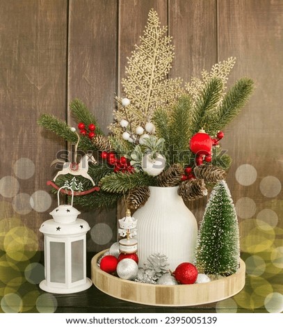 Holiday greeting card Merry Christmas and Happy New Year. On a wooden background there is a vase with decorated spruce branches and a white New Year's lantern. House decoration concept.