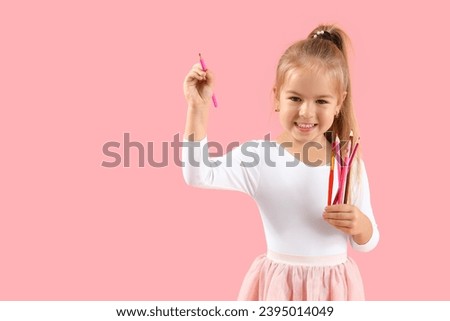 Cute little girl with pencils on pink background