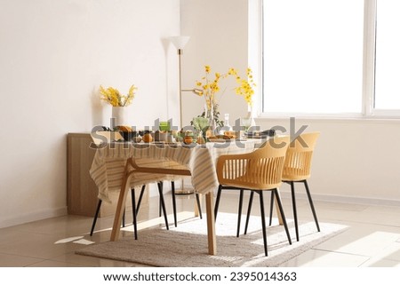 Autumn table setting with flowers and pumpkins in light dining room Royalty-Free Stock Photo #2395014363