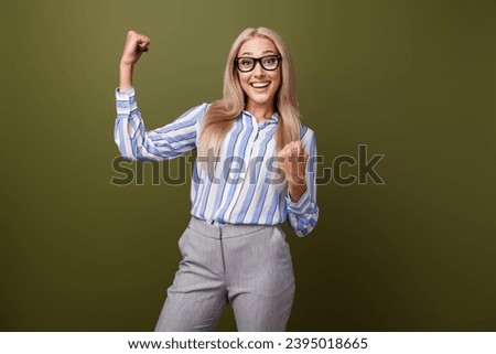 Photo portrait of blonde lovely young lady raise fists celebrate dressed stylish striped garment isolated on khaki color background