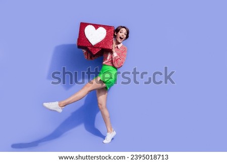 Full size photo of impressed funky woman dressed print shirt holding big social media heart in arms isolated on blue color background