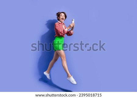 Full size photo of overjoyed woman flying with smartphone in hands impressed by fast intenet connection isolated on blue color background
