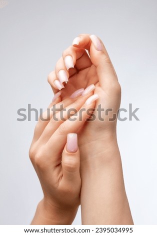 Girl's hands with a beautiful pale pink manicure.  the nail extension procedure in a beauty salon. Professional hand care.