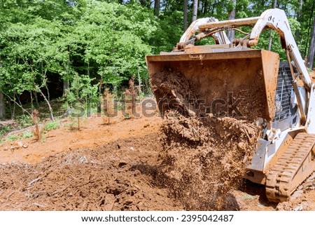 Working with earth with mini bulldozer moving soil for landscaping purposes enhancing property