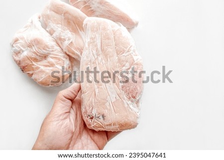 Frozen chicken breast in food plastic wrap. Photo can be used for how to wrap meat for freezer concept. Royalty-Free Stock Photo #2395047641