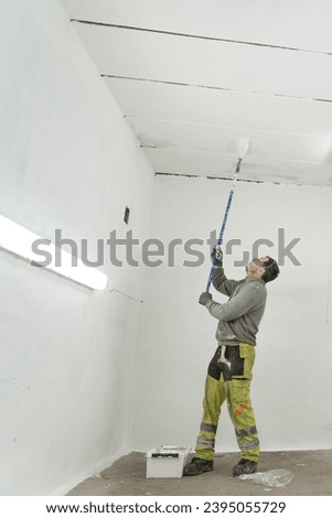 A skilled artisan, using a roller, transforms a large room with precise and masterful painting.