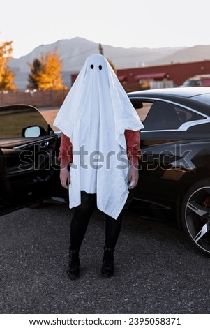 Girl Dressed as Sheet Ghost Standing in front of Mountains