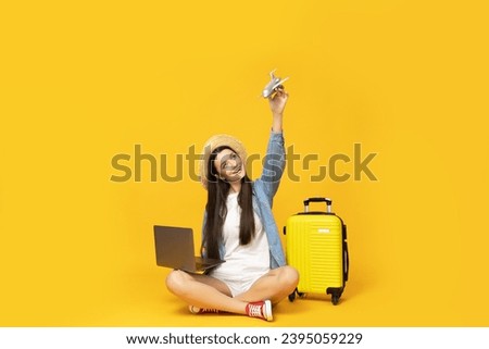 Cute young woman with laptop and suitcase