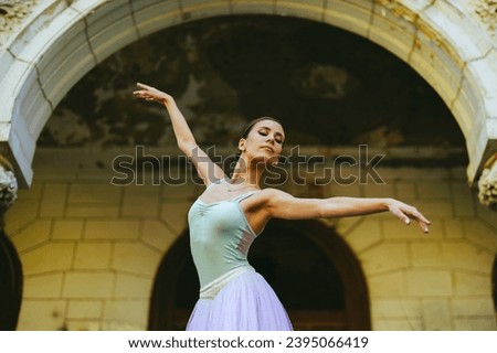 Portrait of a graceful classic ballerina woman with hair tied in a bun dancing while wearing white dress and enjoying in every movement. Grace and motion concept. Copy space. Royalty-Free Stock Photo #2395066419
