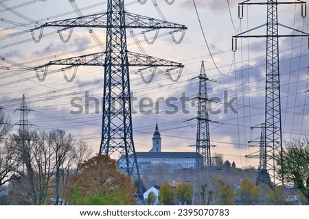 High voltage power lines towards the city of Siegburg with a view of the abbey called Michaelsberg, near Bonn, Germany Royalty-Free Stock Photo #2395070783