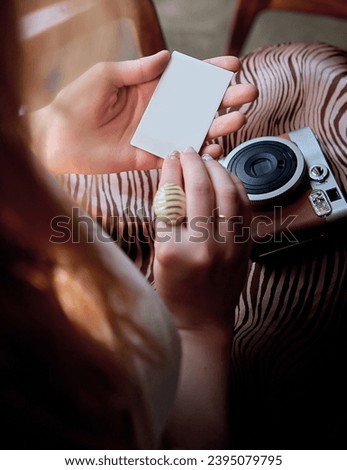 Close view of a girl holding a photo card from a retro camera mockup