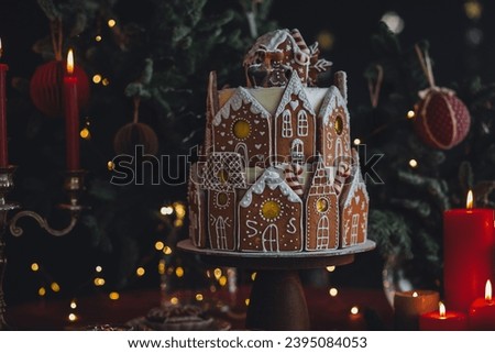 Elegant beautiful handmade gingerbread cookies house with white sugar frosting. Cute magic Christmas village, holiday aesthetics. Cozy home atmosphere, holiday family time. Interior decor, candles