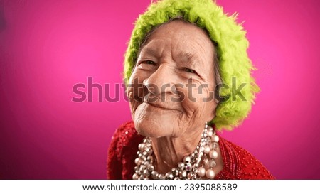 Smiling fisheye portrait caricature of funny elderly woman smiling with green hat isolated on pink background.