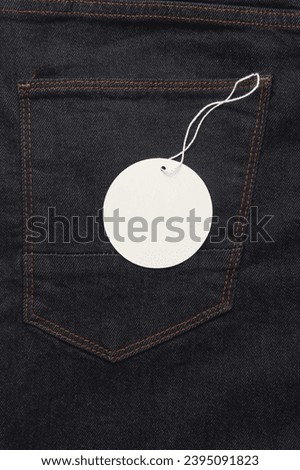 Jeans with white blank tag on a string. Shopping, sale concept. Template for design
