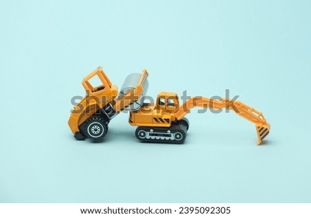 Toy asphalt paver and excavator on blue background