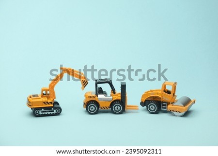 Toy forklift, asphalt paver and excavator on blue background