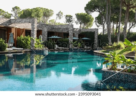 Swimming pool, tropical plants and sunbeds at luxury resort