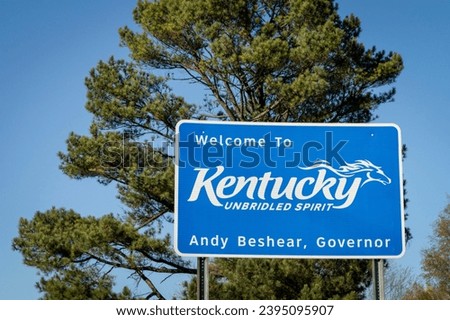Welcome to Kentucky, Unbridled Spirit - roadsign at state border with Tennessee with a pine tree in background.