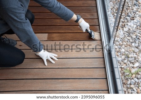 Wood floor sealing and varnishing, hand holding a brush applying transparent protective coat Royalty-Free Stock Photo #2395096055