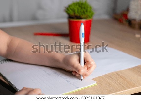 schoolchild doing homework, copying words English, child writes in notebook, assignments involving English language exercises, acquisition, vocabulary building in school setting, Bilingual Education Royalty-Free Stock Photo #2395101867
