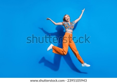 Full length photo of satisfied cute girl dressed print top flying palms presenting empty space offer isolated on blue color background