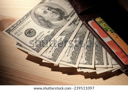 Brown Wallet with credit cards and dollar banknotes over wooden background. Shallow depth of field.