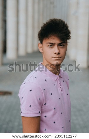 Serious teen boy standing at street looks at camera with proud confident face. Youth. Brunette male posing outdoors. Purposeful people. Royalty-Free Stock Photo #2395112277