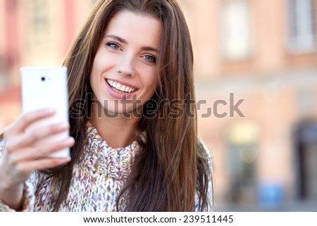 pretty young woman taking a picture on town. Smiling girl. Winter