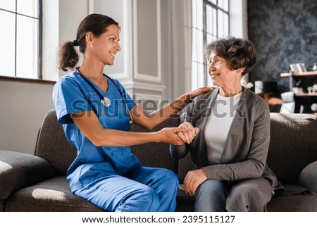 Supportive caregiver nurse doctor medical worker taking care of old woman, hugging embracing elderly patient at home, aiding curing doing treatment in hospice Royalty-Free Stock Photo #2395115127